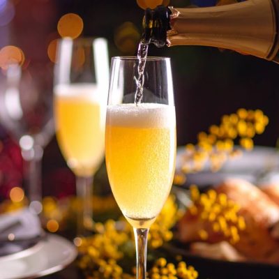 Close-up of Champagne being poured into a Mimosa cocktail at a brunch party