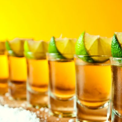 Row of tequila shots with salt and lime wedges