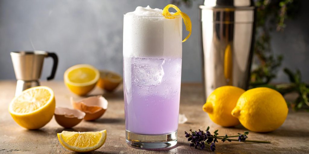 Collins glass with violet drink and foamy head with lemons