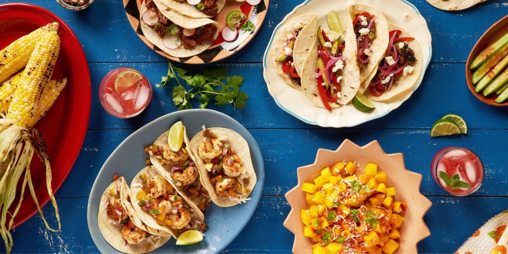 A vibrant Mexican feast with colourful dishes and cocktails, set on a festive table decorated for Cinco de Mayo.