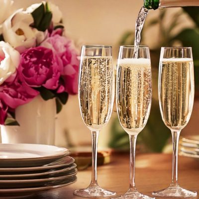 Pouring shot of Champagne into a flute glass, peonies in the background