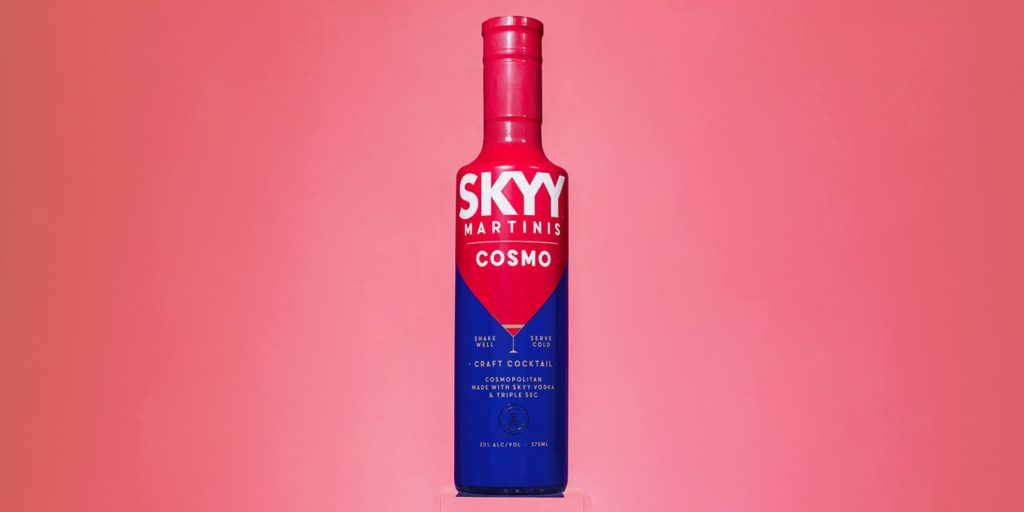 A bold, modern SKYY Cosmo Martini bottle against a pink gradient background.