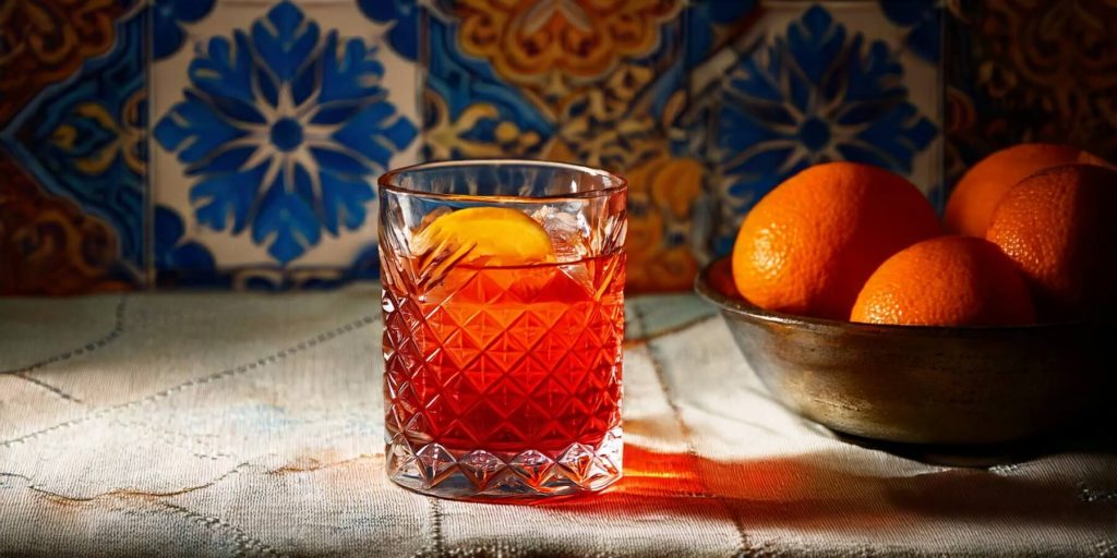 Close-up of an Oaxacan Negroni, bowl of oranges to the side