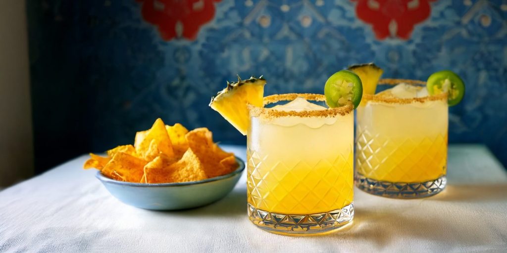 Two Pineapple Jalapeño Mexzcalita agave spirit cocktails with pineapple and jalapeño garnish