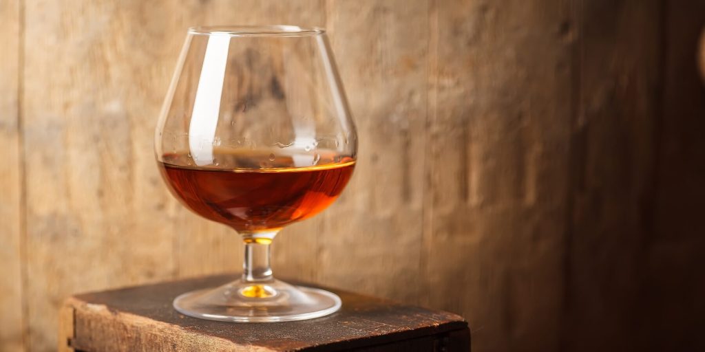Balloon snifter filled with Dutch brandy resting on a wooden crate, photo by hiddenhallow/Adobe Stock