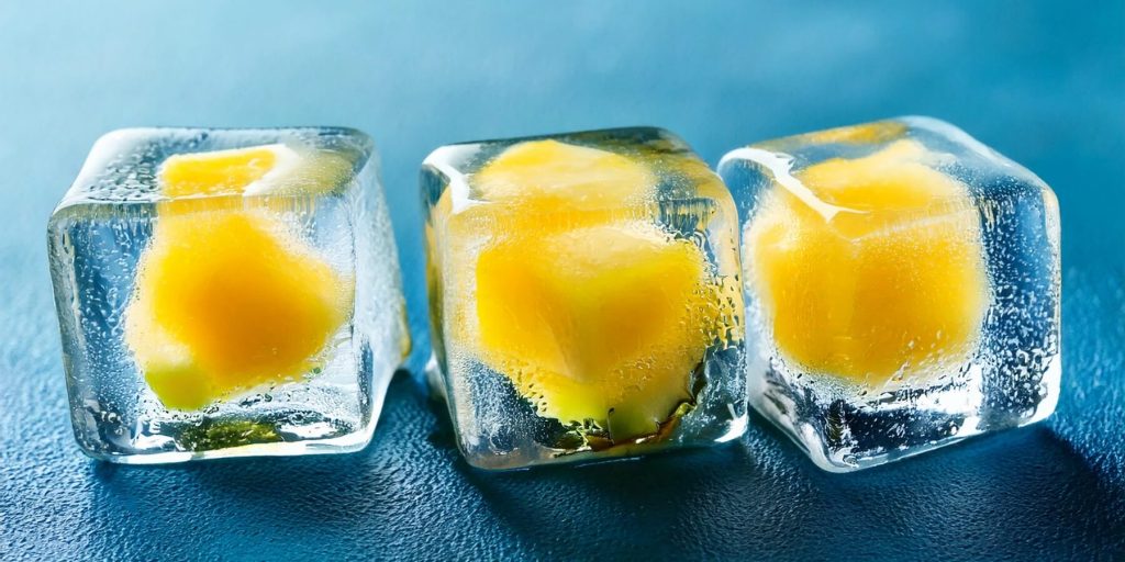 Close-up of three ice cubes with pineapple frozen on the inside