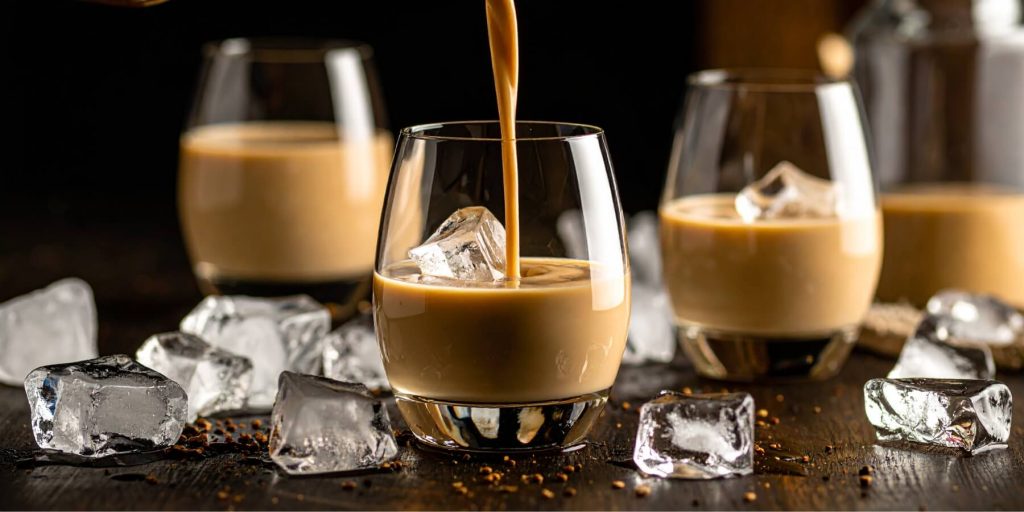 Close-up of Irish cream liqueur being poured into an ice-filled glass