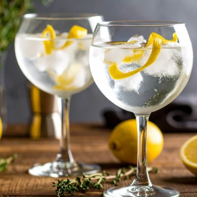 Close-up of two Gin and Tonic cocktails in ice-filled glasses with lemon peel garnish