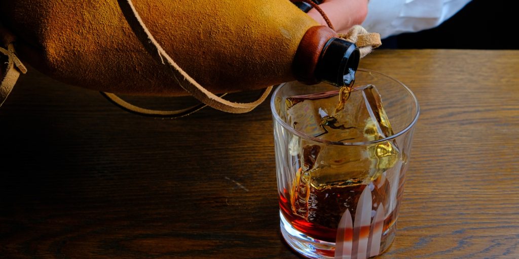 Close up of a cocktail being poured into a rocks glass