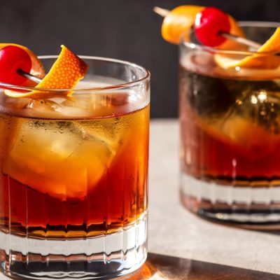 Two glasses of Old Fashioned cocktails with ice and garnish