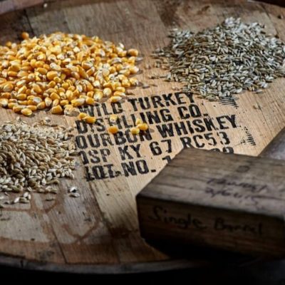 The top of a Wild Turkey bourbon barrel with piles of corn, wheat and rye grains with a wooden mallet