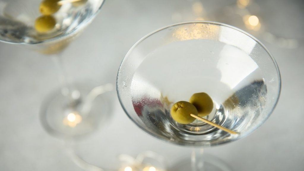 Close up top view of a Reverse Martini cocktail garnished with olives, presented on a white surface