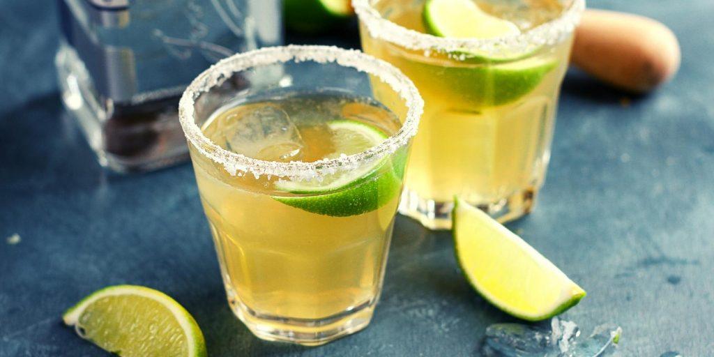 A Mezcal Margarita cocktail garnished with a lime wedge and chili salt rim.