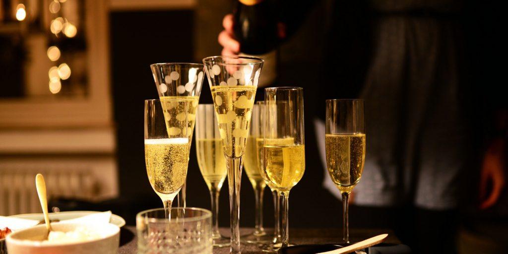A tray full of bubbly Apple Cider Bellini cocktails in a room decorated for a party