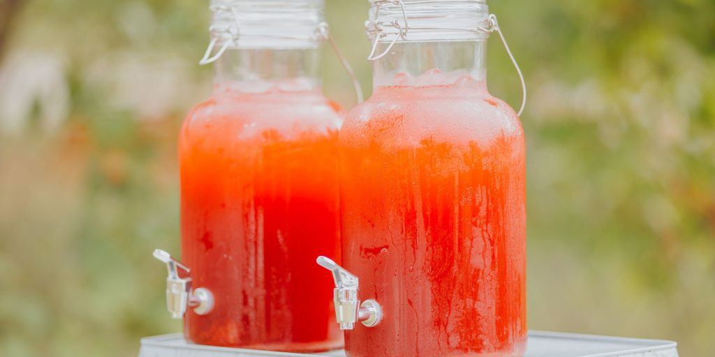 Two large containers of Apple pie punch on a table outdoors on a sunny day