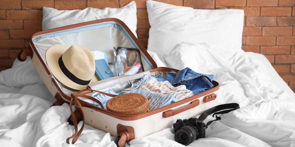 An open packed suitcase on a bed, ready for a honeymoon.