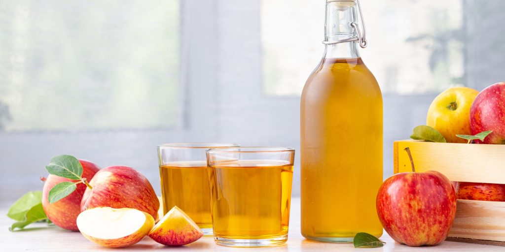 A bottle of apple cider with two glasses