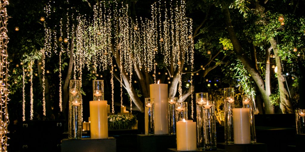 A table of candles with decorative hanging string lights