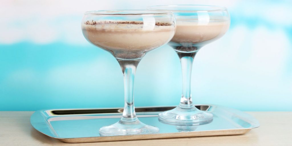 Two creamy White Rabbit cocktails on a silver tray against a bright blue backdrop
