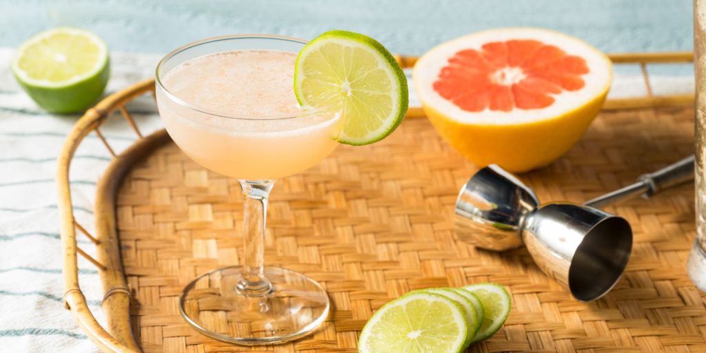 Close up of a refreshing Hemingway Daiquiri presented on a rattan serving platter along with some fresh fruit
