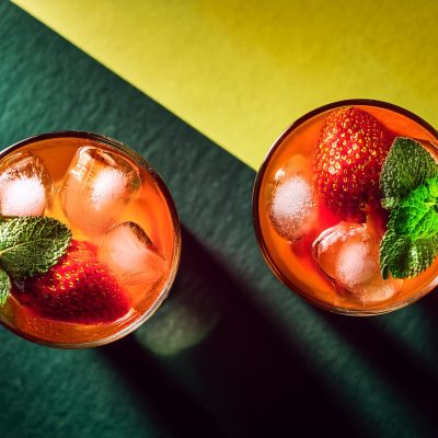 Two Wray and Nephew Rum Punch cocktails on a yellow and green surface shot from above