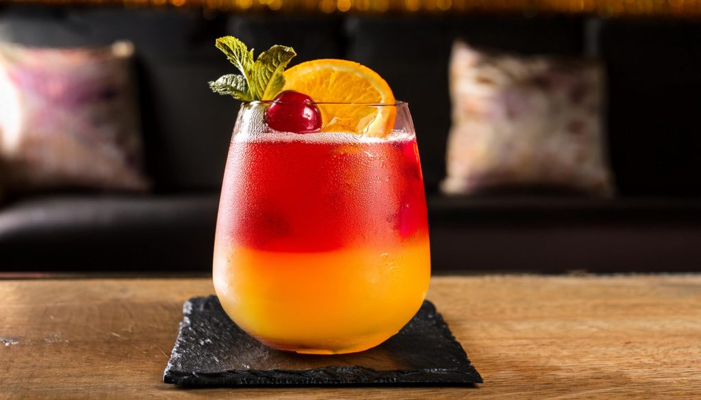 Close-up of a Wray and Nephew Italian Breeze cocktail with orange, mint and cherry garnish