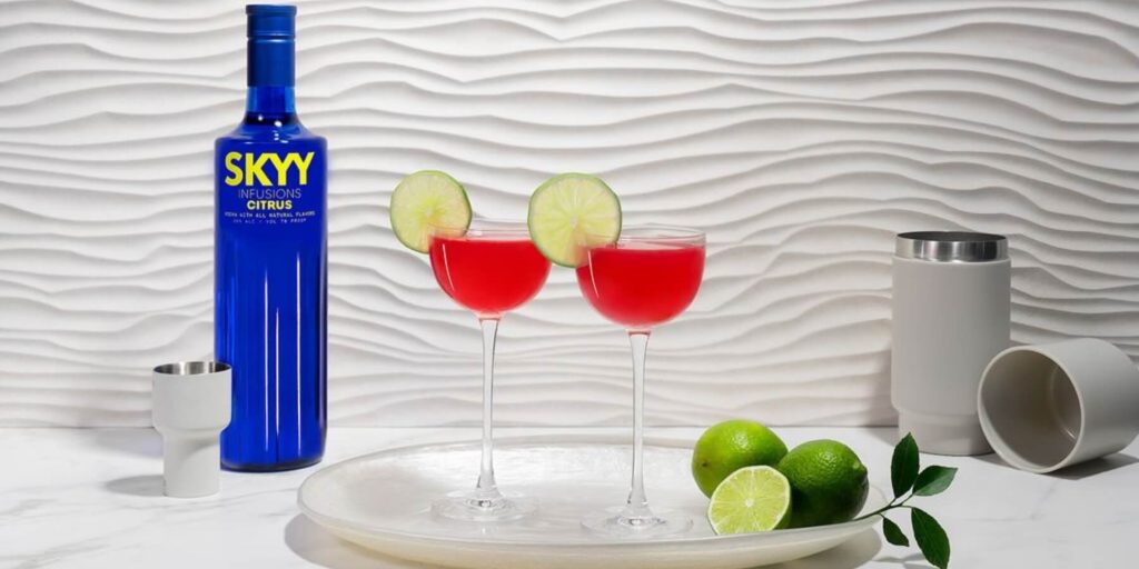 A close-up shot of a SKYY Vodka bottle with a strong shadow cast on a neutral wall, emphasizing the brand’s iconic blue glass design. The minimalist aesthetic highlights the timeless appeal of the vodka bottle. 