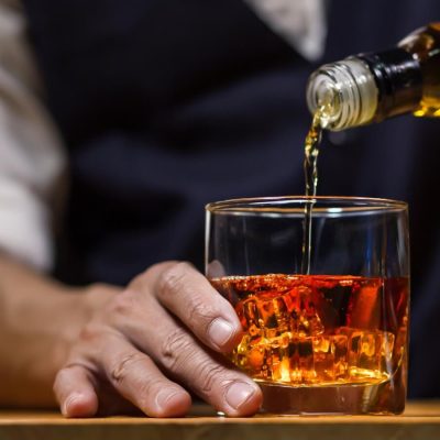 Close-up of a bartender pouring bourbon into a glass, photo by maeching Adobe Stock Images