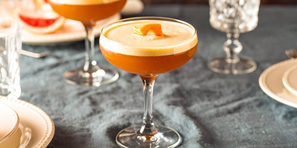 Two Maple Brown Derby cocktails on a grey tablecloth in a light bright home setting
