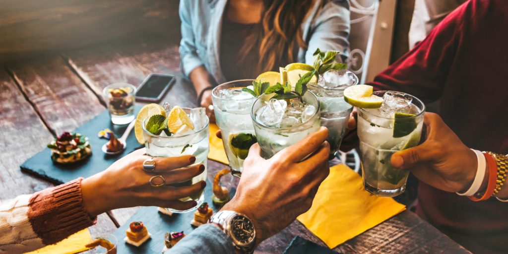 A group of friends toasting with cocktails around a table.