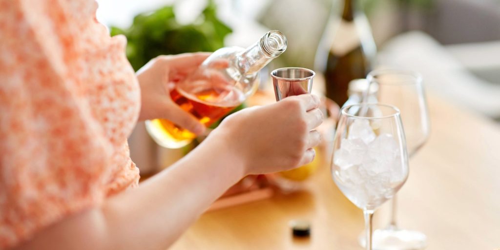 A woman measuring out Aperol to make a Spritz cocktail.
